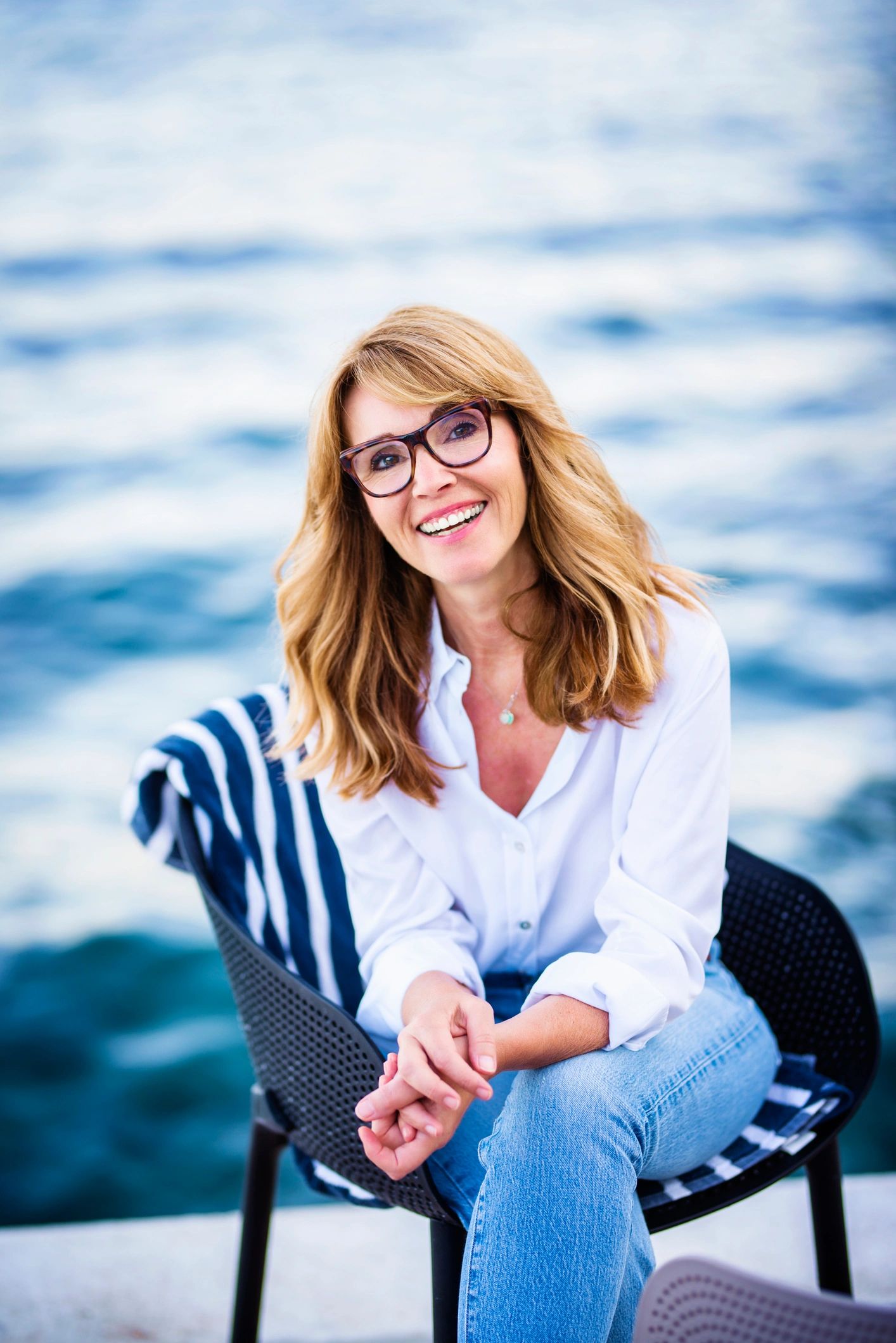 Beautiful mature woman sitting on chair and relaxing by the sea